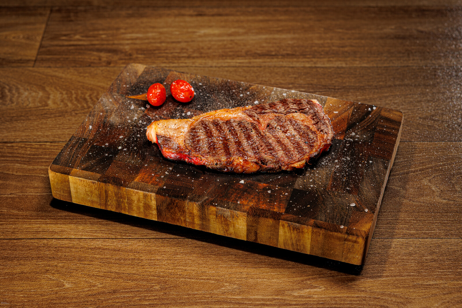 Bistecca alla griglia servita su tagliere di legno con pomodorini