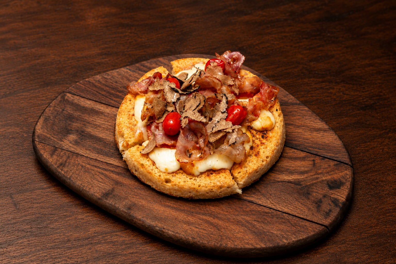 Focaccella al tartufo nero con pancetta, scamorza e pomodorini, sul tagliere di legno